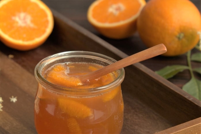 Glas Orangenmarmelade mit frischen Orangen