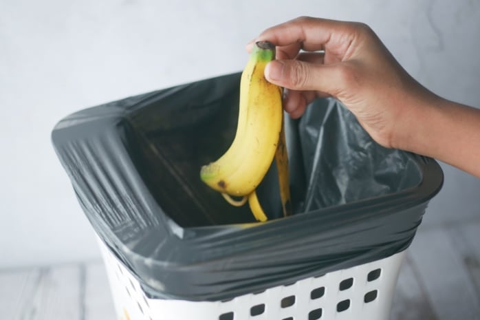 Mann wirft Bananenschale in den Müll