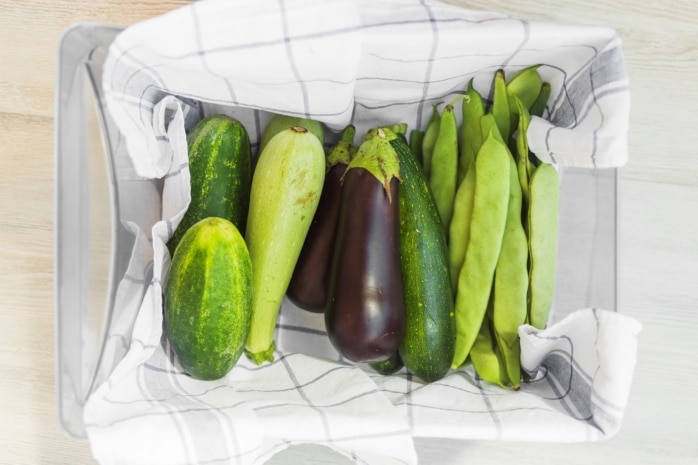 Gurken und anderes Gemüse in Geschirrhandtuch in Box lagern