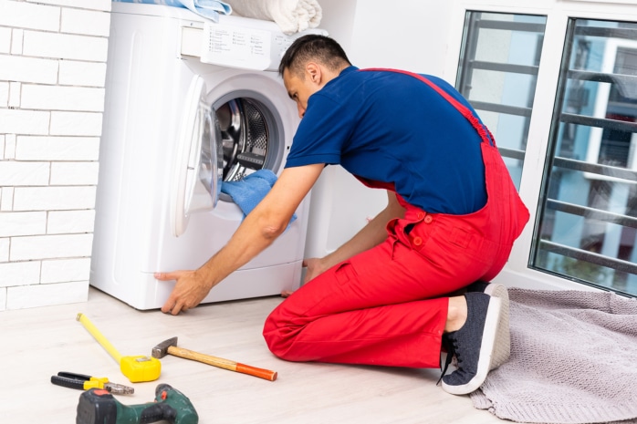 Waschmaschine wird von einem Handwerker ausgerichtet