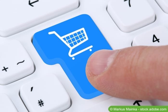 Online shoppen - Finger drückt Warenkorbsymbol auf Tastatur